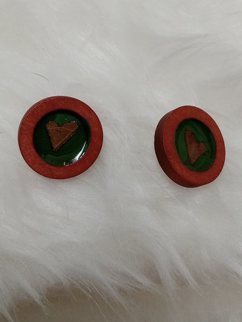 Handmade earrings on a wooden base with a piece of punched-out tree leaf